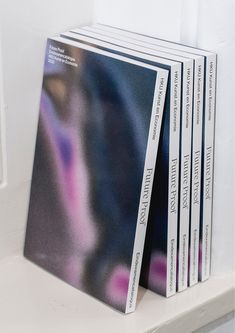 four books are stacked on top of each other in front of a white wall with blue and pink designs