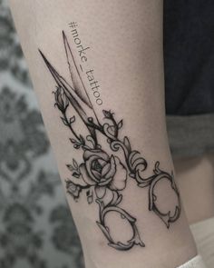 a tattoo with scissors and roses on the leg, which is also in black ink