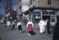 an old photo of people walking down the street in traditional korean garb and hats