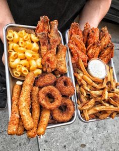 two trays filled with different types of food next to some fries and macaroni