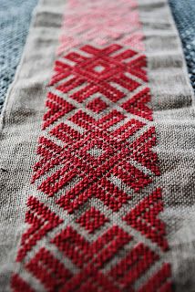 a red and white cross stitched design on fabric