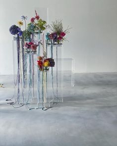 three tall vases with flowers in them sitting on the floor next to each other