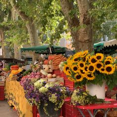 an outdoor market with sunflowers and other vegetables