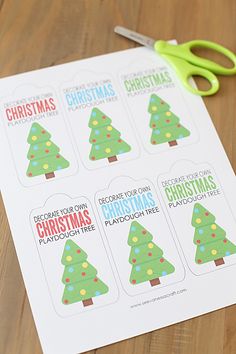 a pair of scissors sitting on top of a piece of paper with christmas tree stickers