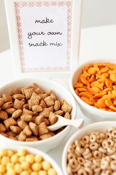 four white bowls filled with cereal next to a sign that says make your own snack mix