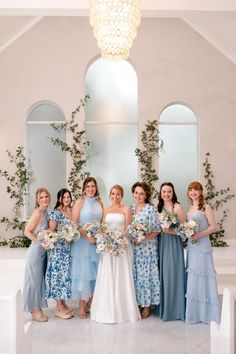 a group of women standing next to each other in front of a chandelier