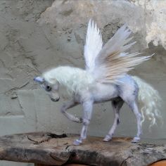 a white horse with wings standing on top of a wooden table next to a stone wall