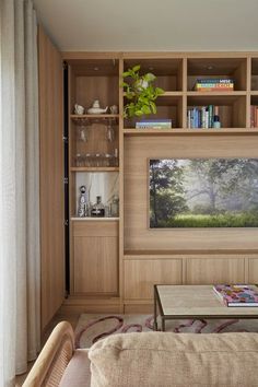 a living room filled with furniture and a flat screen tv mounted on a wall next to a window