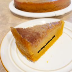 a piece of pie sitting on top of a white plate next to a yellow cake