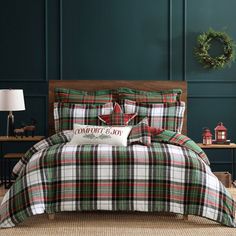 a plaid comforter set with christmas decorations on the headboard and foot board in front of a dark green wall