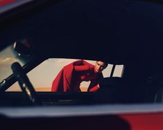 a man in a red shirt is sitting in the back seat of a car with his hands on his hips