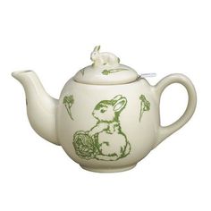 a white teapot with green rabbit designs on the side and a flower in the middle