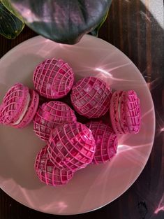 a white plate topped with pink waffles on top of a wooden table next to a potted plant