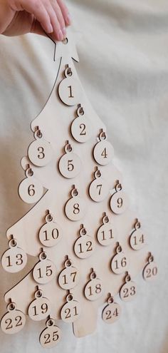 a person holding a wooden christmas tree with numbered numbers on the front and back side