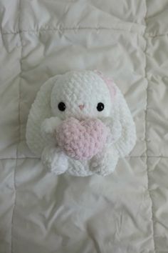 a crocheted stuffed animal laying on top of a white bed sheet with its eyes open