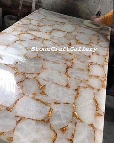 a table that has some kind of white and gold marble on it with the words stonecraft gallery above it