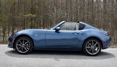 a blue sports car parked in front of some trees