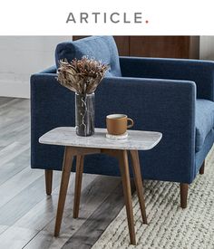 a coffee table with a vase on it next to a blue chair