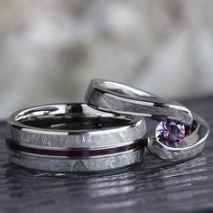 two wedding bands with a purple stone in the center