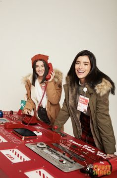 two women standing next to each other in front of a red table with electronic equipment on it