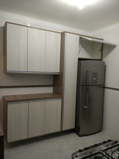 a kitchen with cabinets and a refrigerator in the middle, next to a stove top oven