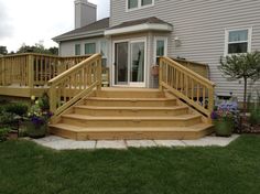 a wooden deck with steps leading up to the front door