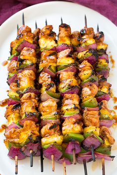 several skewers of food sitting on a white plate with purple cloth around it