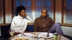 two people sitting at a table with plates of food and drinks in front of them