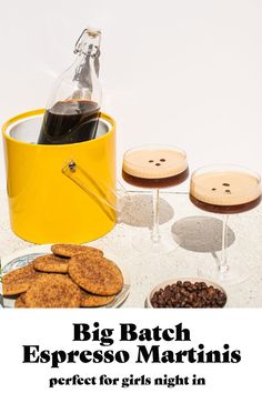 a yellow bucket filled with cookies next to two wine glasses