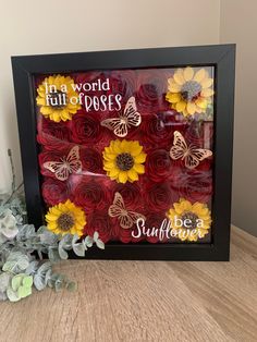 a frame with sunflowers and butterflies on it, sitting next to a plant