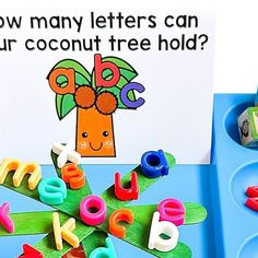 a blue tray with letters and magnets on it next to a sign that says how many letters can your coconut tree hold?