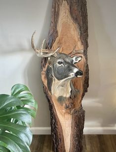 a wooden carving of a deer with antlers on it's head, next to a potted plant