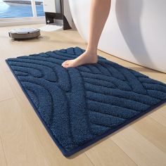 a person's feet on a blue rug in front of a white bathtub