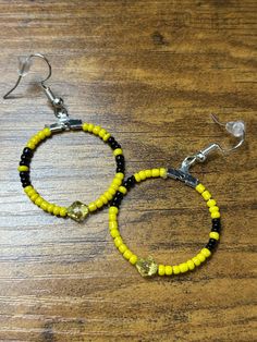 Medium sized hoop earrings with yellow and black beads. Made using glass Czech beads and bicone bead in the middle. Yellow Hoop Earrings With Ear Wire, Yellow Beaded Small Hoop Jewelry, Yellow Dangle Hoop Earrings With Ear Wire, Yellow Small Hoop Earrings With Ear Wire, Yellow Beaded Small Hoop Earrings, Yellow Beaded Round Hoop Earrings, Small Yellow Beaded Hoop Earrings, Yellow Adjustable Beaded Hoop Earrings, Adjustable Yellow Hoop Earrings With Colorful Beads