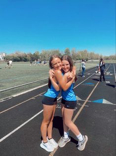 two girls hugging each other on a track