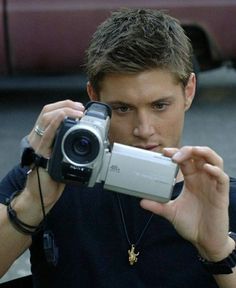 a young man holding up a camera to take a picture