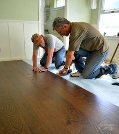 two men working on a wood floor in a house