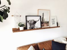 a living room filled with furniture and framed pictures on the wall above a leather couch