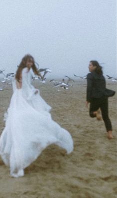 two women running on the beach with seagulls in the background