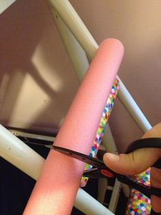 someone is cutting the end of a pink tube with scissors