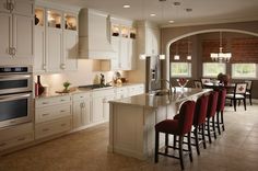 a large kitchen with white cabinets and red bar stools in front of an oven