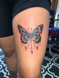 a woman's leg with a butterfly tattoo on the side of her thigh,