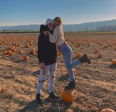 a man and woman standing in a field full of pumpkins