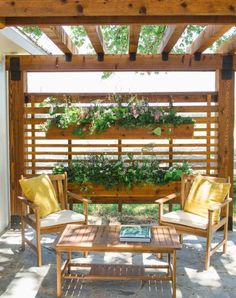 two chairs and a table under a pergolated area with plants growing on it