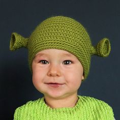 a little boy wearing a green knitted hat with two ears on it's head