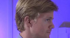 a close up of a person wearing a suit and tie in front of a purple background