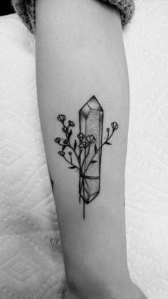 a black and white photo of a tattoo with flowers on the side of the arm