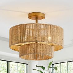 a chandelier hanging from the ceiling in a room with large windows and potted plants