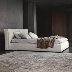 a white bed sitting in the middle of a room next to a rug on top of a wooden floor