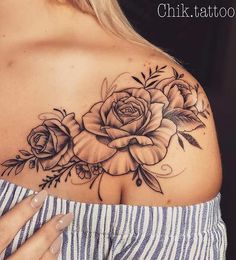 a woman's shoulder with flowers and leaves tattoo on her left side breast area